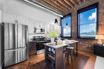A kitchen with a stainless steel refrigerator and wooden floors.